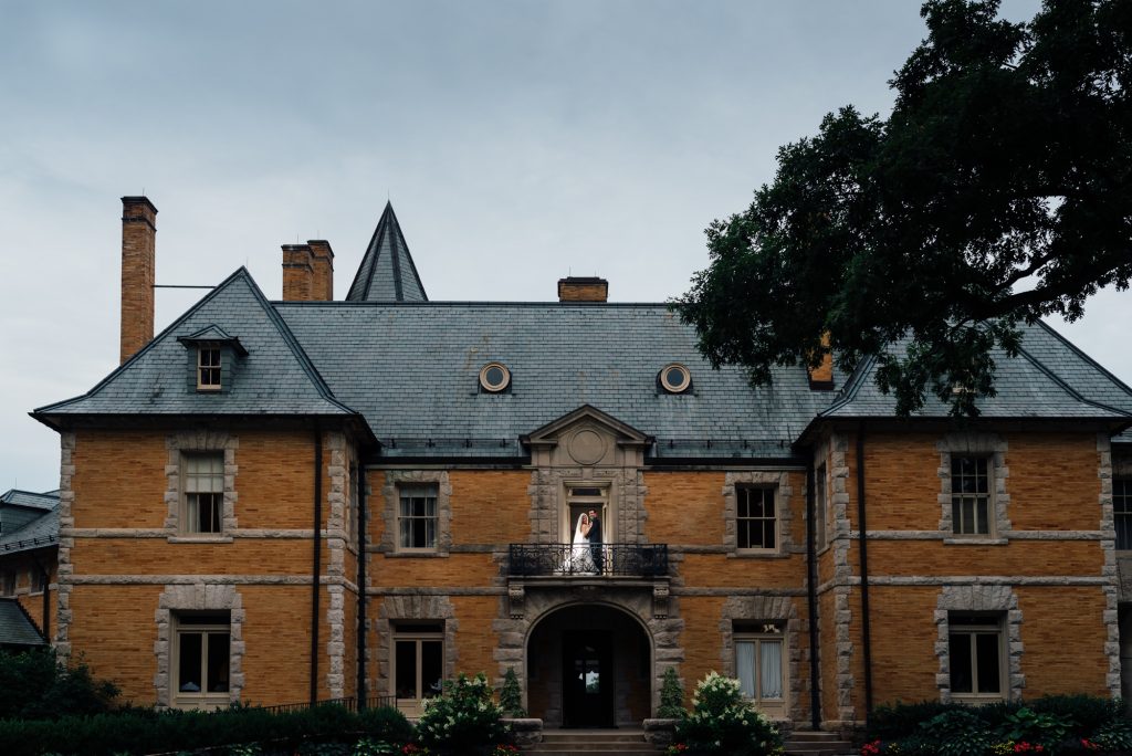 Bride and groom on balcony of Cairnwood Estate mansion