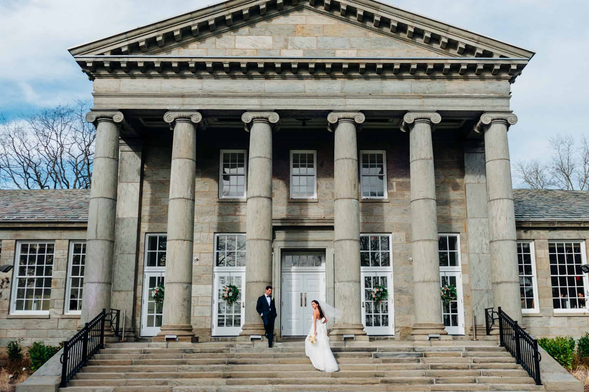 Bride and groom posing on steps of Ballroom at Ellis Preserve