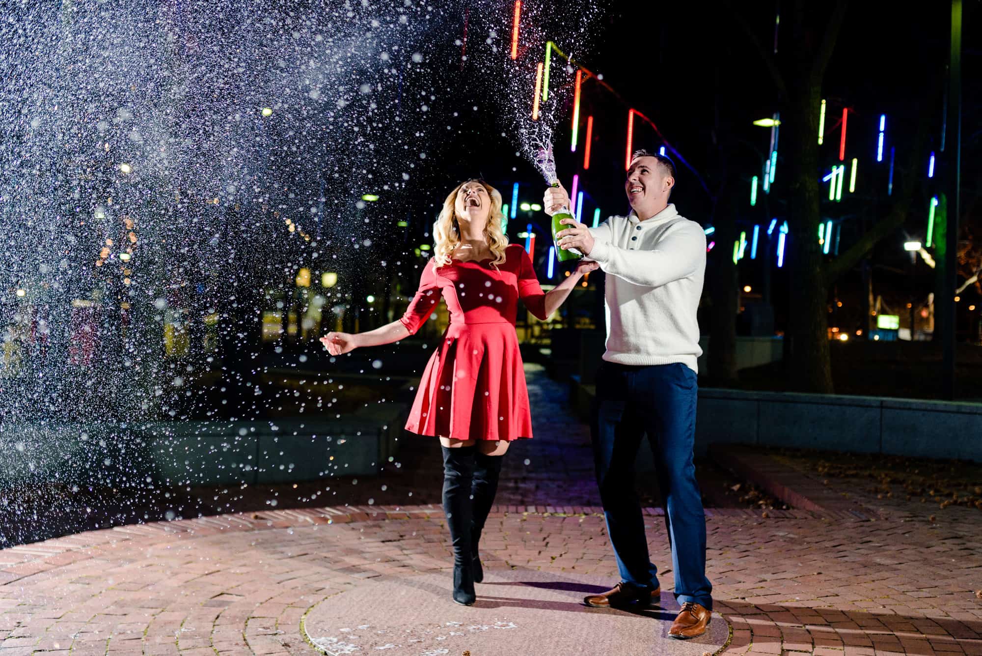 couple popping wine during their e-session at Penn's landing