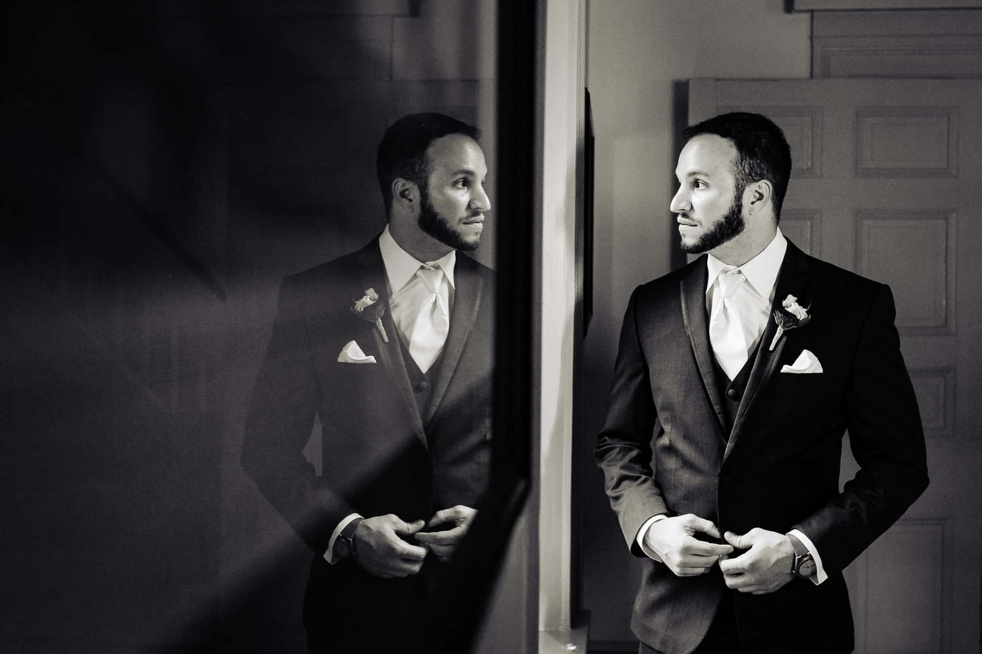 groom looking at his reflection black and white shot