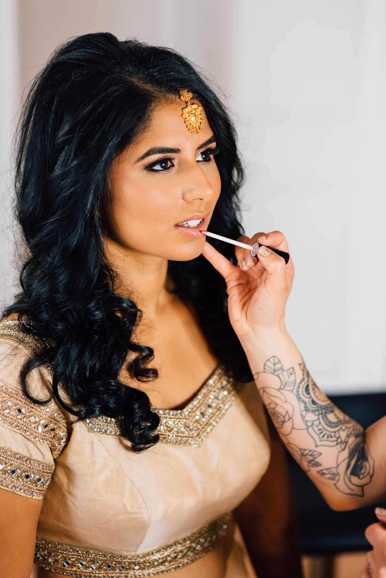 wedding makeup, artist applying lipgloss to bride