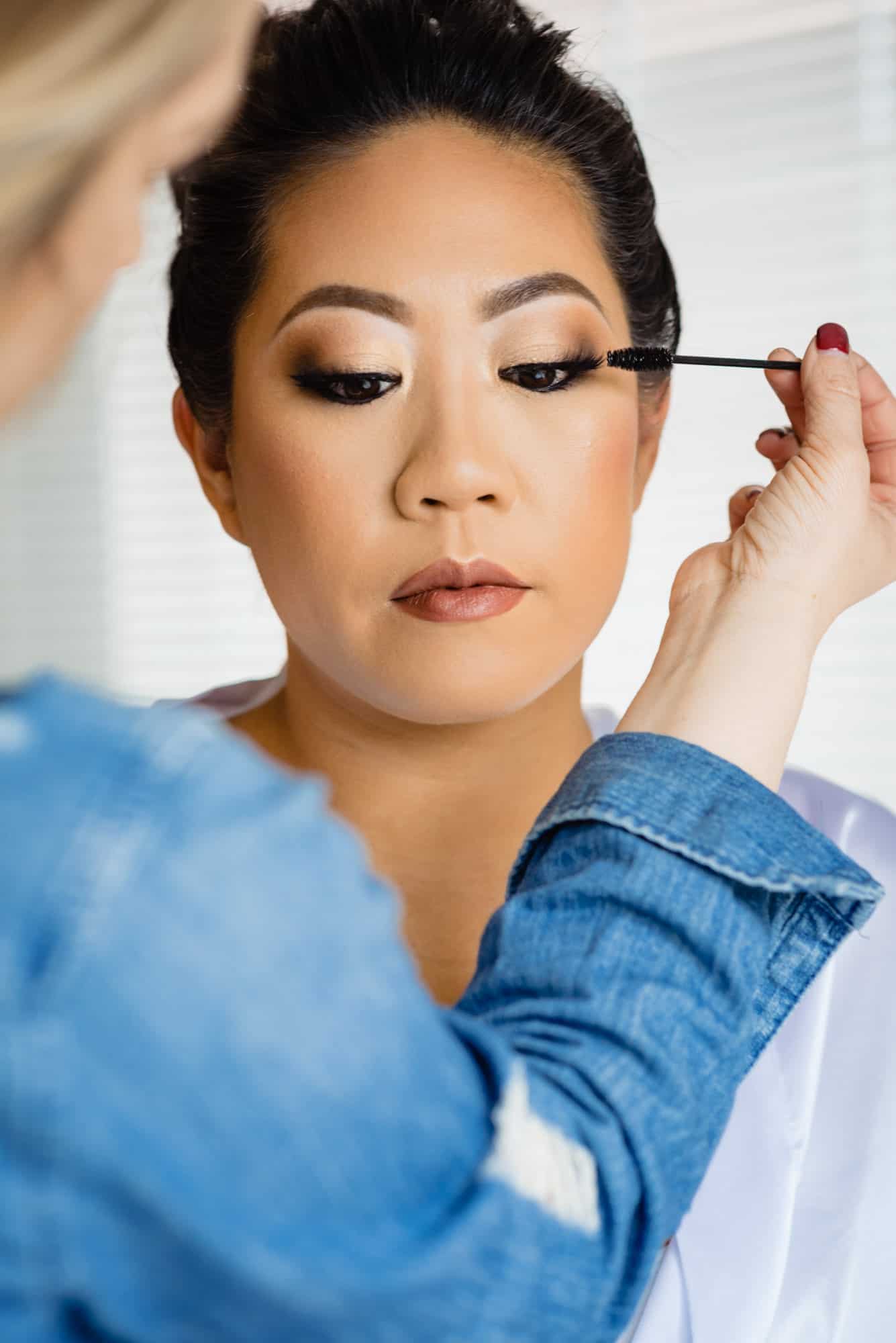 wedding makeup, closeup of artist applying mascara to bride