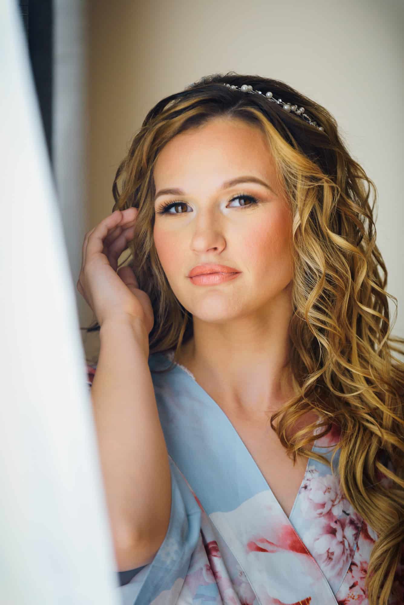 wedding makeup, bride pulling back piece of hair looking into window