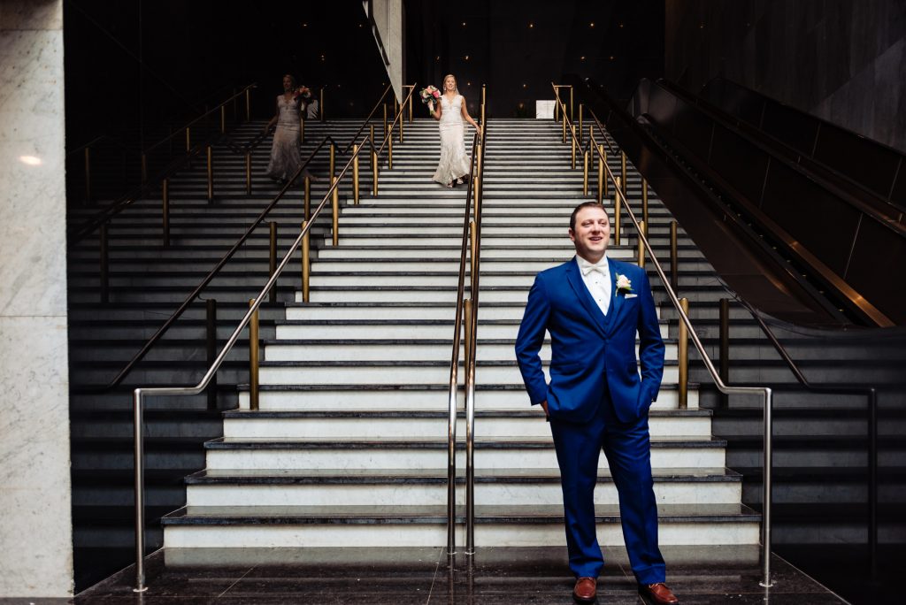 wedding day, bride coming down the stairs to reveal her first look as groom is waiting at the bottom