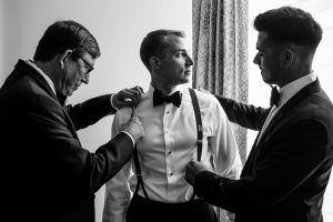 Ritz Carlton Philadelphia Wedding|groom looking out window while best man and father adjust his suspenders