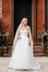 bride in front of city door smiling and looking off camera