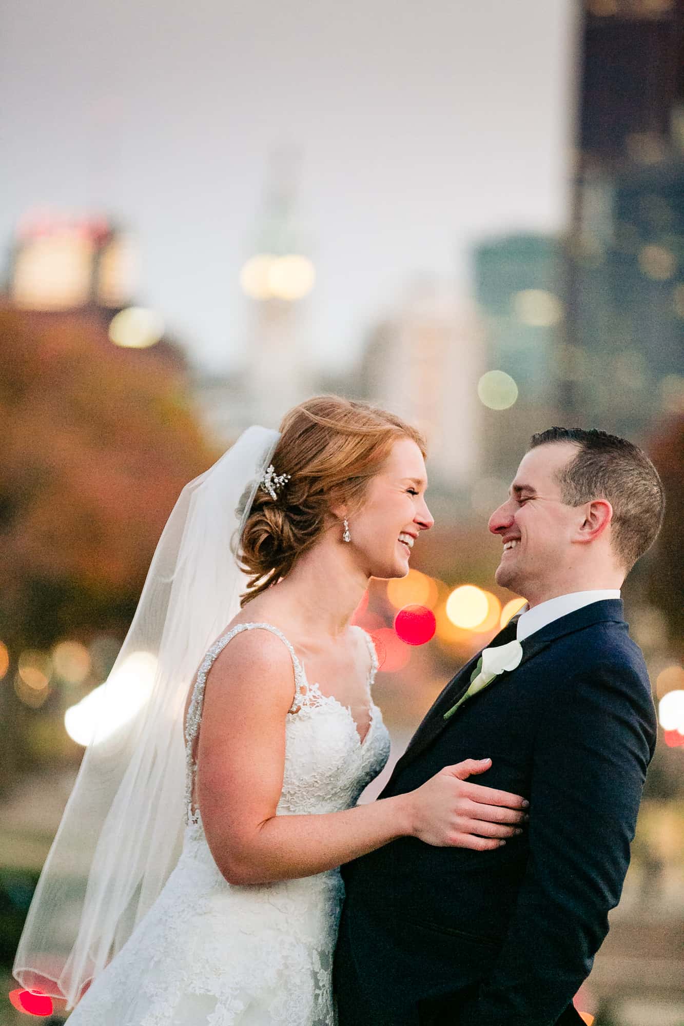 Bride and groom laughing with city lights behind them