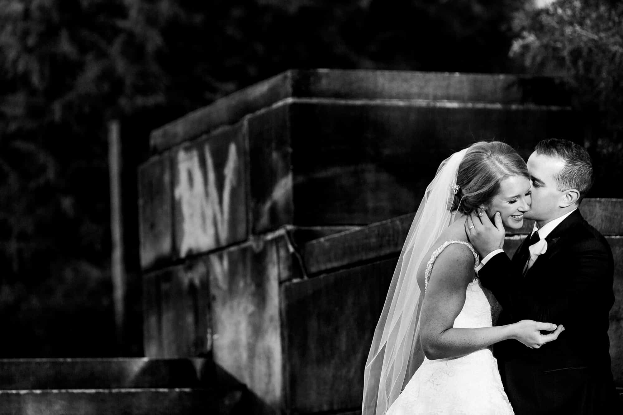 Black and white image of groom kissing brides cheek