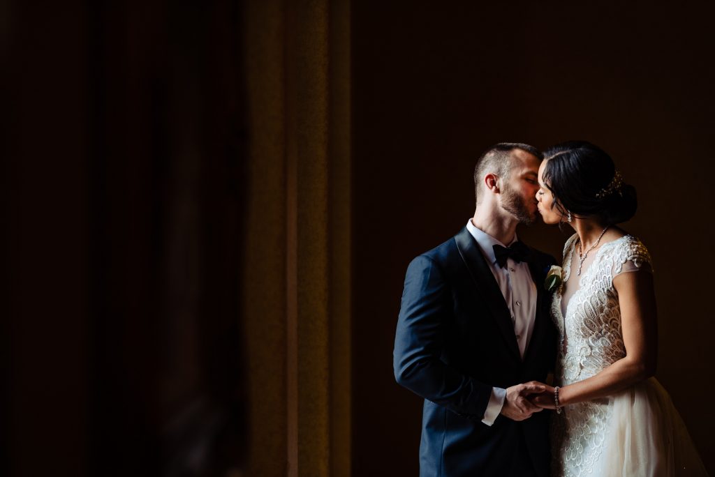 Bride and groom kissing in beautiful window light