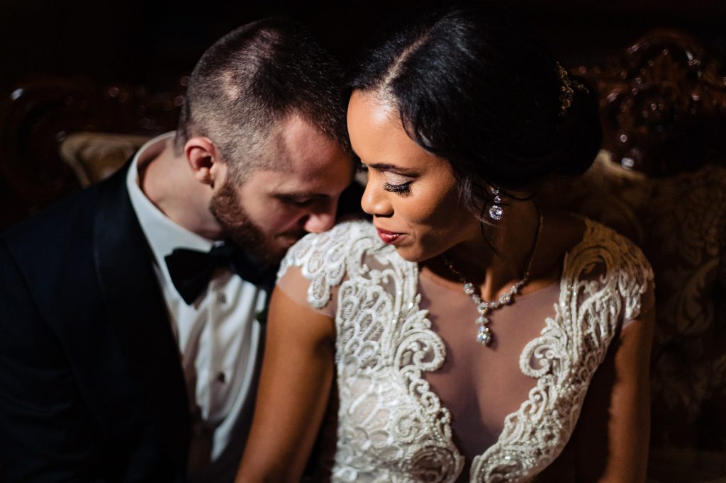 Groom kissing brides shoulder in dramatic light