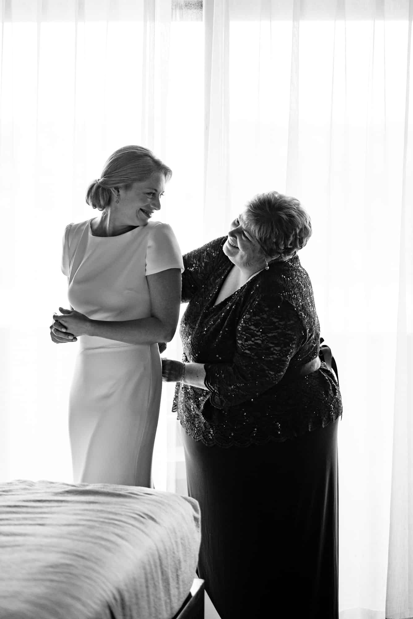 black and white shot of the bride and her mother smiling at each other