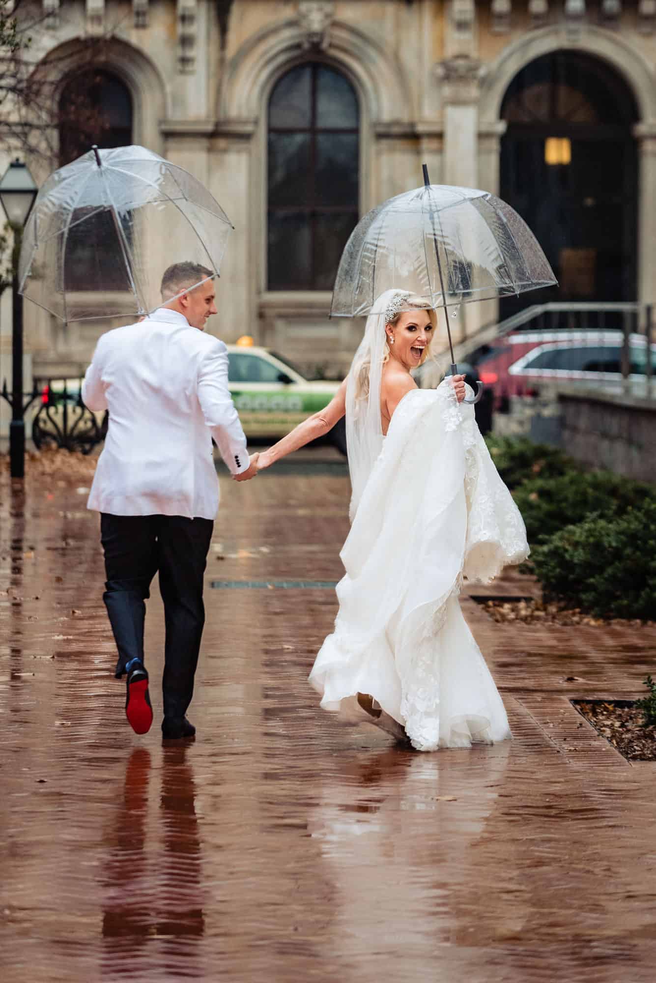 newlyweds holding an umbrella on How to Prepare for Rain on Your Wedding Day