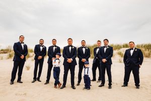 groom and groomsmen with little boys poses for the camera