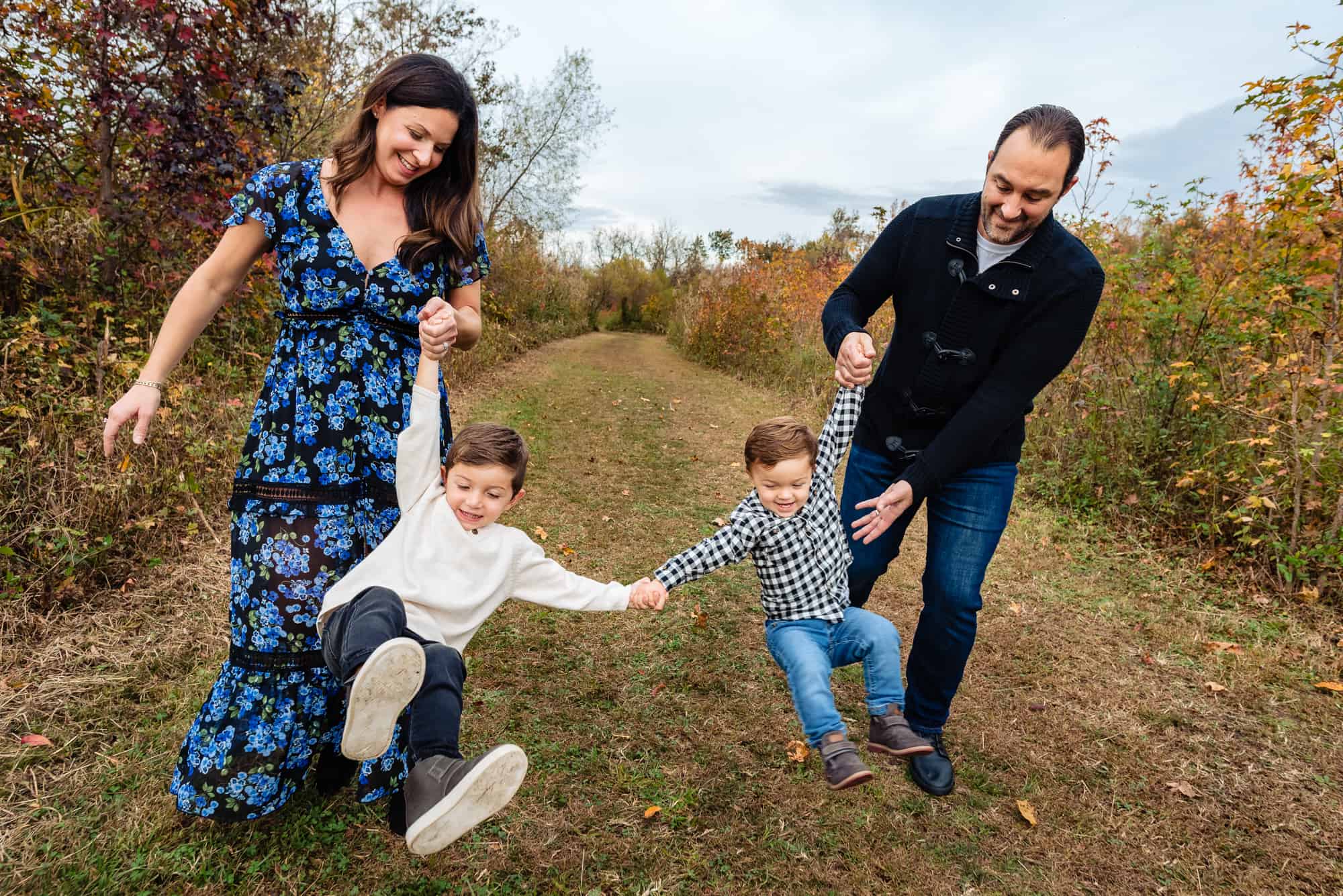 mother and father holding the hands of their two playing kids for their stress free family photo session