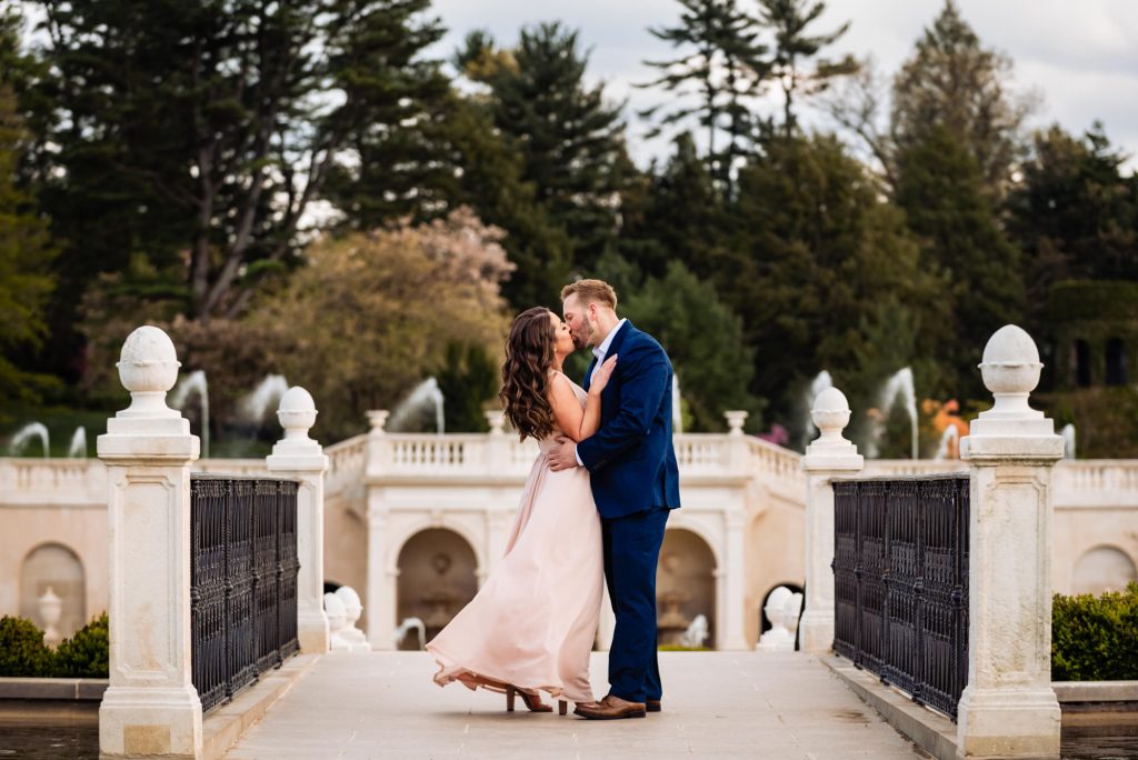 couple taking a pose on top of a white bridge during their Longwood Gardens Spring e-session