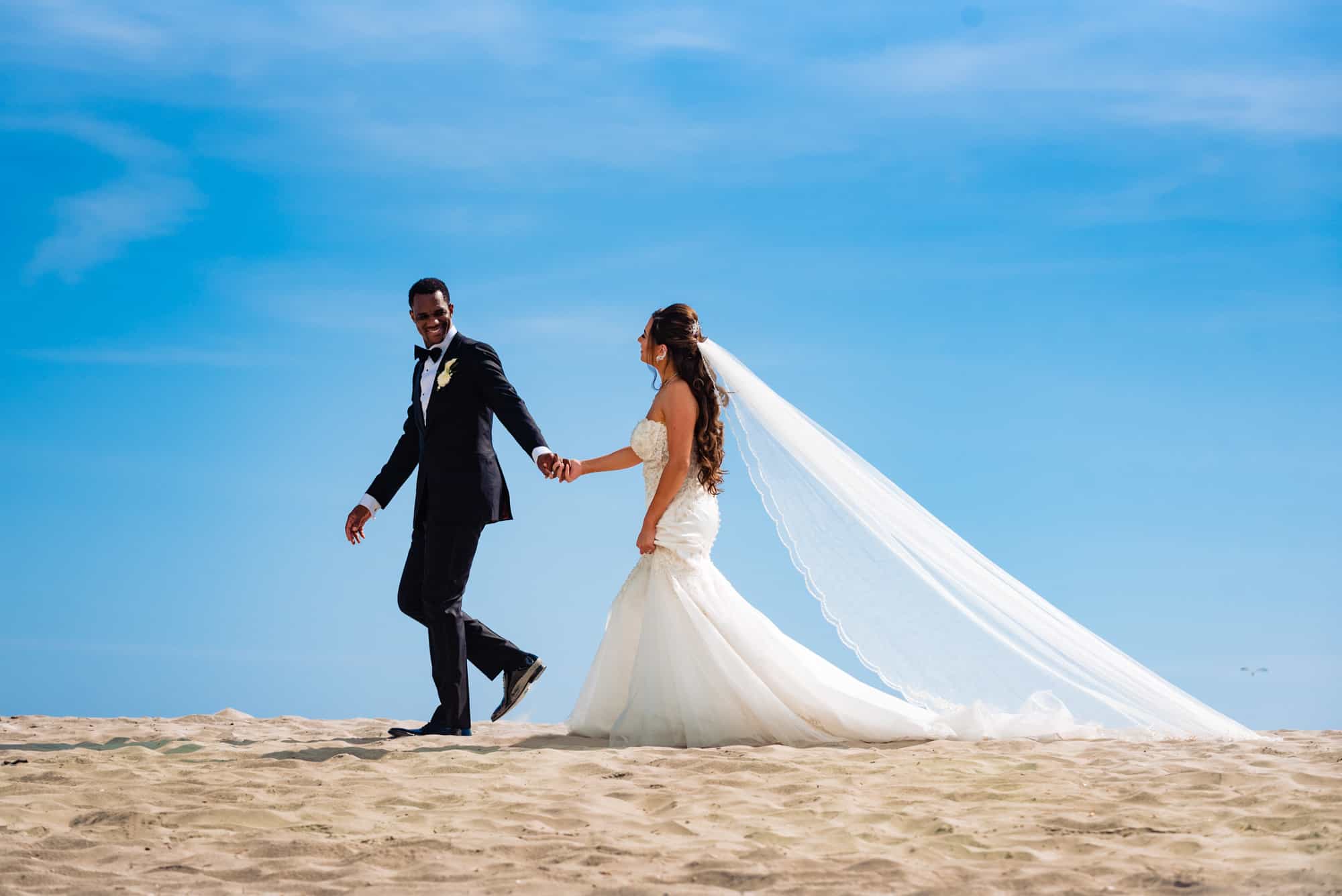 bride and groom walks along the beach line