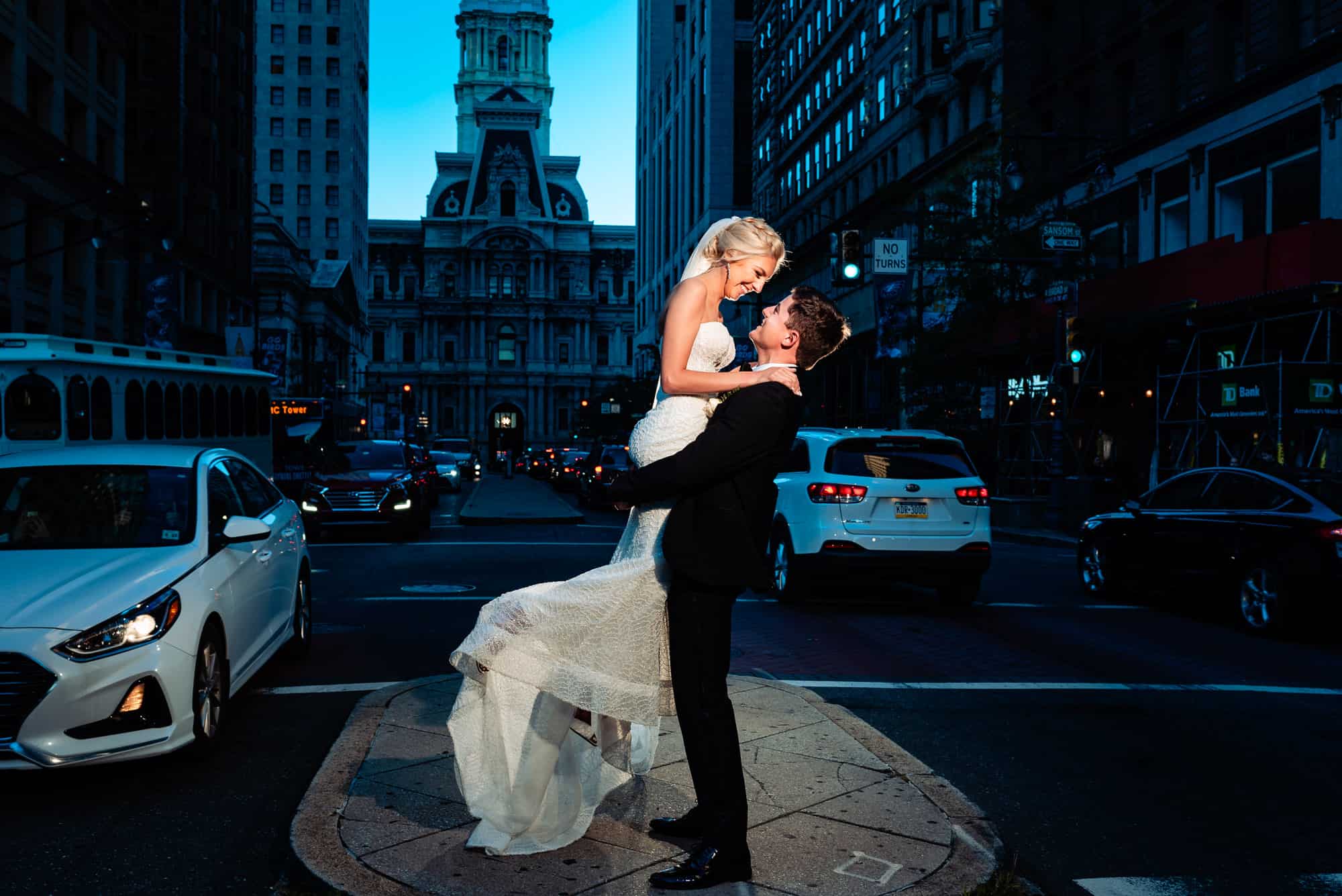 bride and groom taking a pose at the middle of the street with the city hall at the back