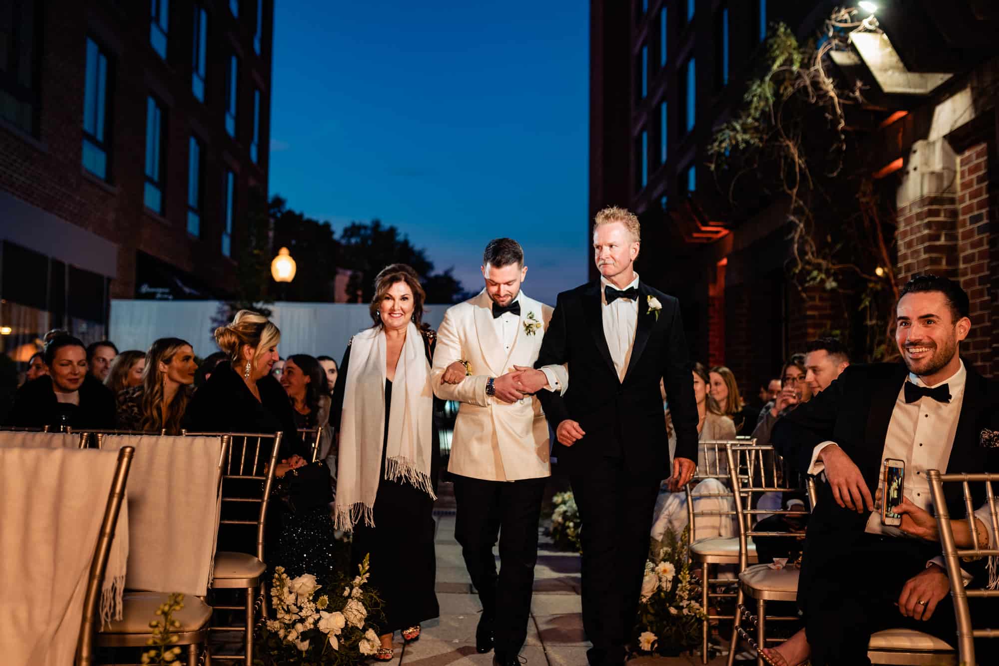 groom walking down the aisle with his parents