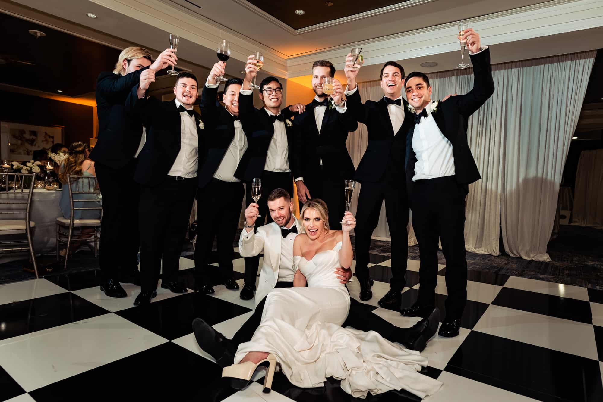 bride and groom sitting on the dancefloor surrounded by thier groomsman at their Four Seasons DC wedding