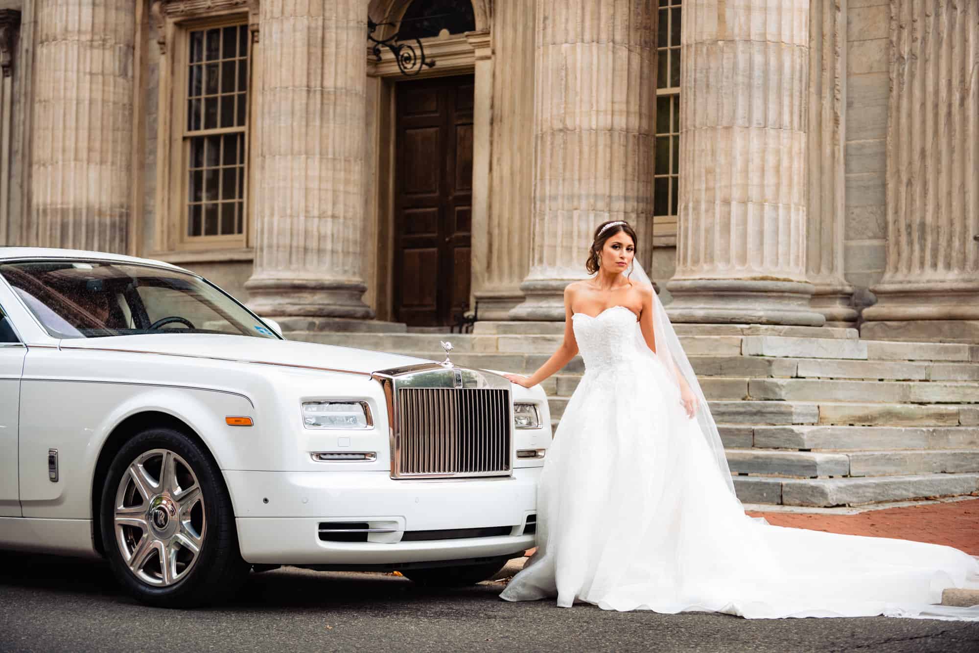 bride is taking a pose beside her bridal car