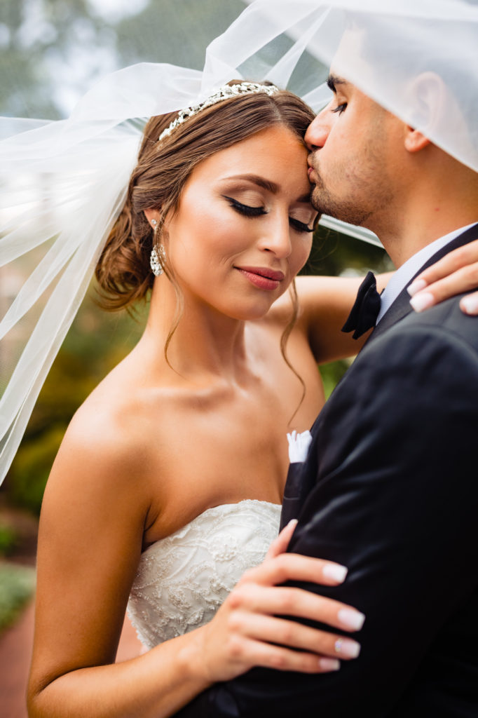 Portrait shot of the groom kissing the bride's forehead