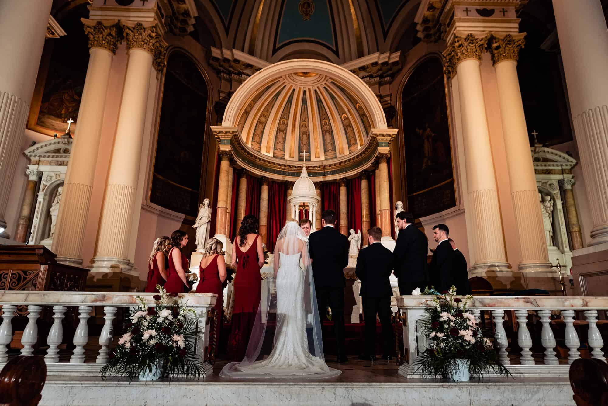 bride and groom surrounded by the entourage at the altar