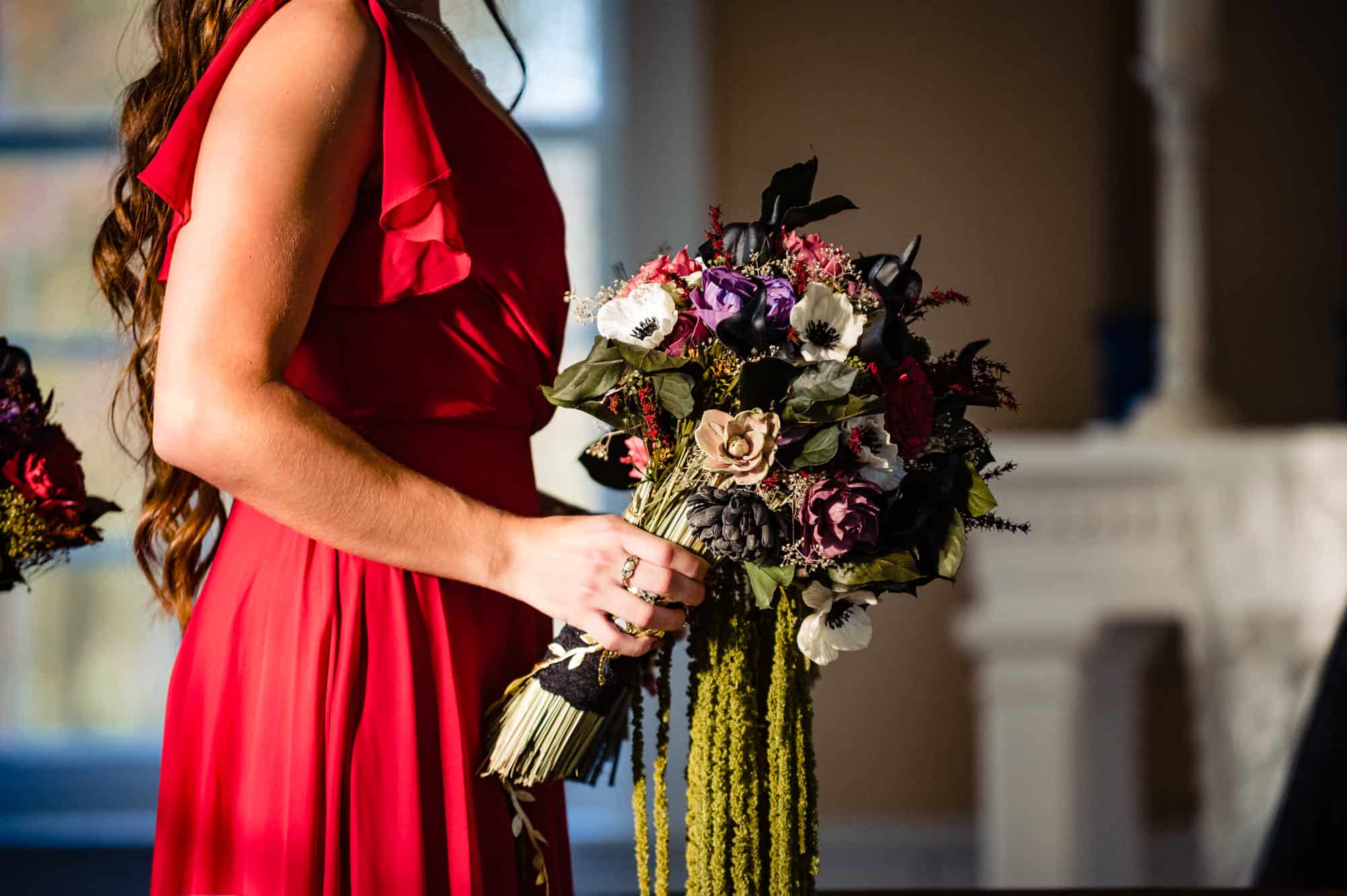 bridesmaid holding the bride's bouquet during the wedding ceremony at bride and groom standing at church altar during wedding ceremony at Allaire state park historic chapel