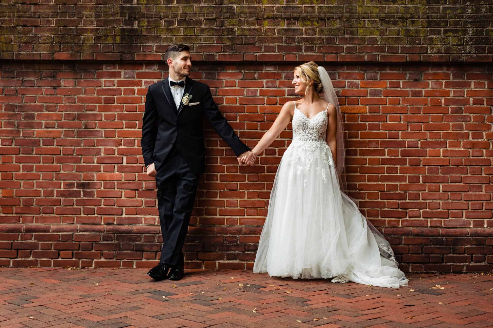 smiling couple pose before the camera while holding hands together