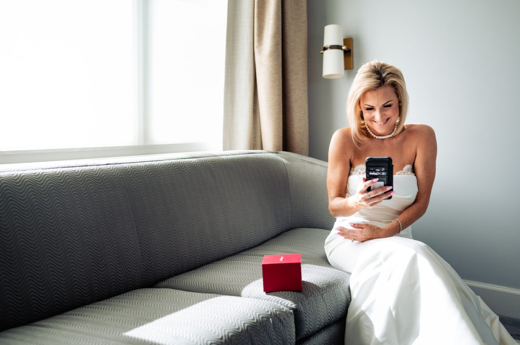 a smiling bride reading a text message at her suite at Ritz-Carlton Half Moon Bay
