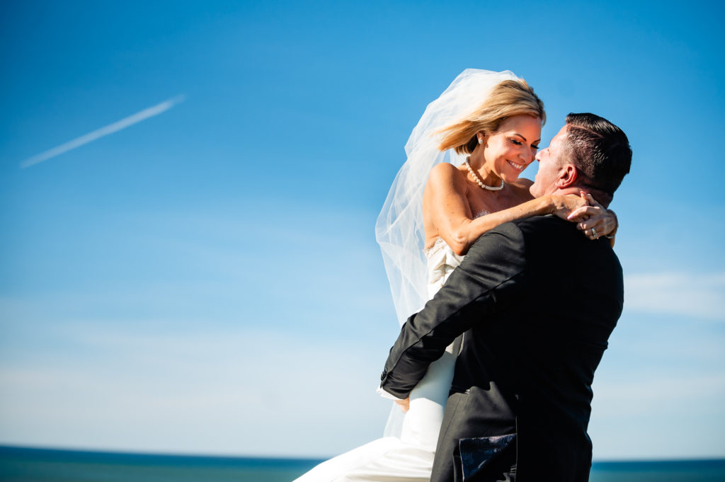 groom carrying his bride on a cliff before the wedding outside the Ritz-Carlton Half Moon Bay