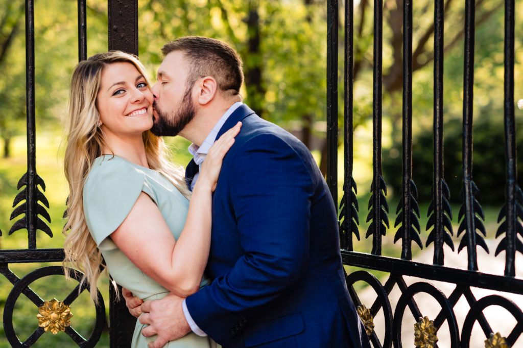 man is kissing his future wife on the cheeks during their old city e-session