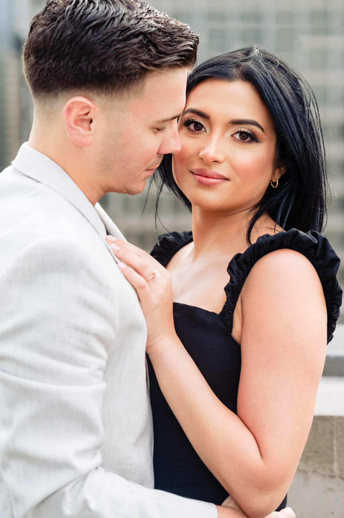 bride-to-be smiling at the camera while man holds her during their center city engagement session