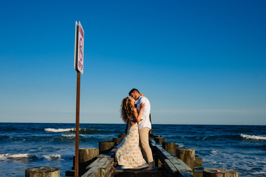 couple kissing on the pier during their margate new jersey engagement shoot