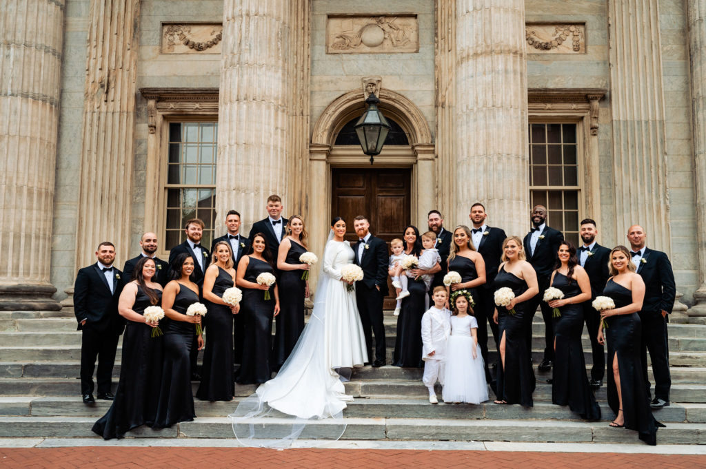 long shot of the couple with the bridesmaids and groomsmen infront of the cathedral