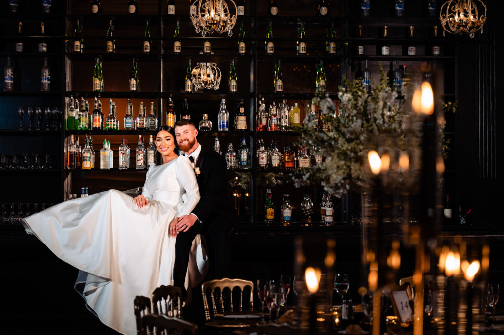 bride and groom poses at the bar station