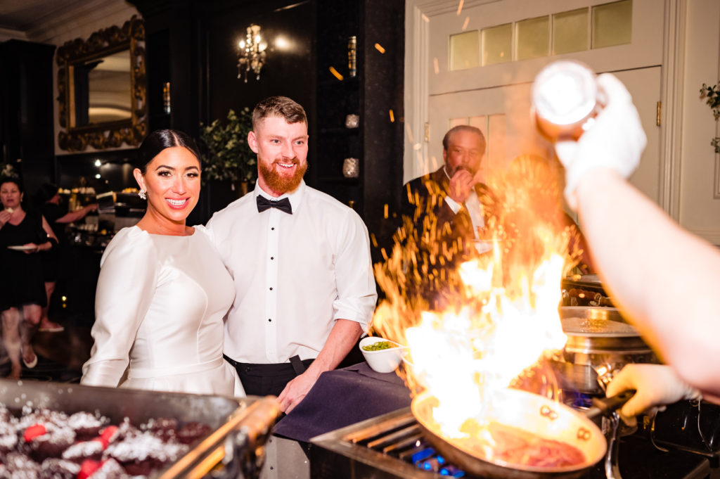 newlywed watching the chef prepare the food in front of the them