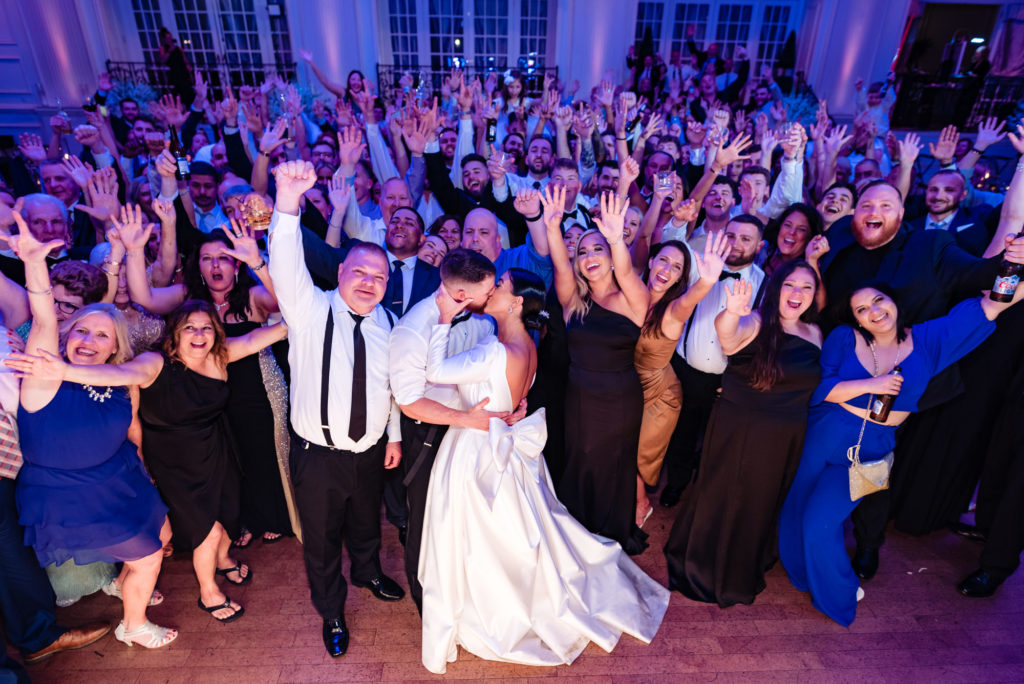 bride and groom kissing with everyone posing for the camera