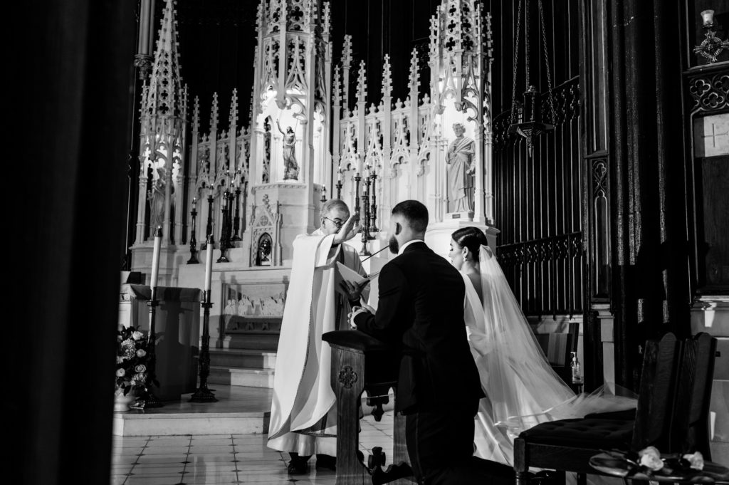 black and white shot of the couple kneeling in front of the altar