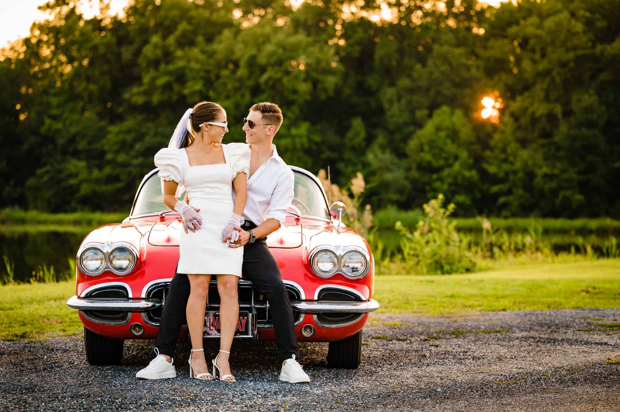 couple sitting on the hood of their 1958 Chevrolet Corvette roadster