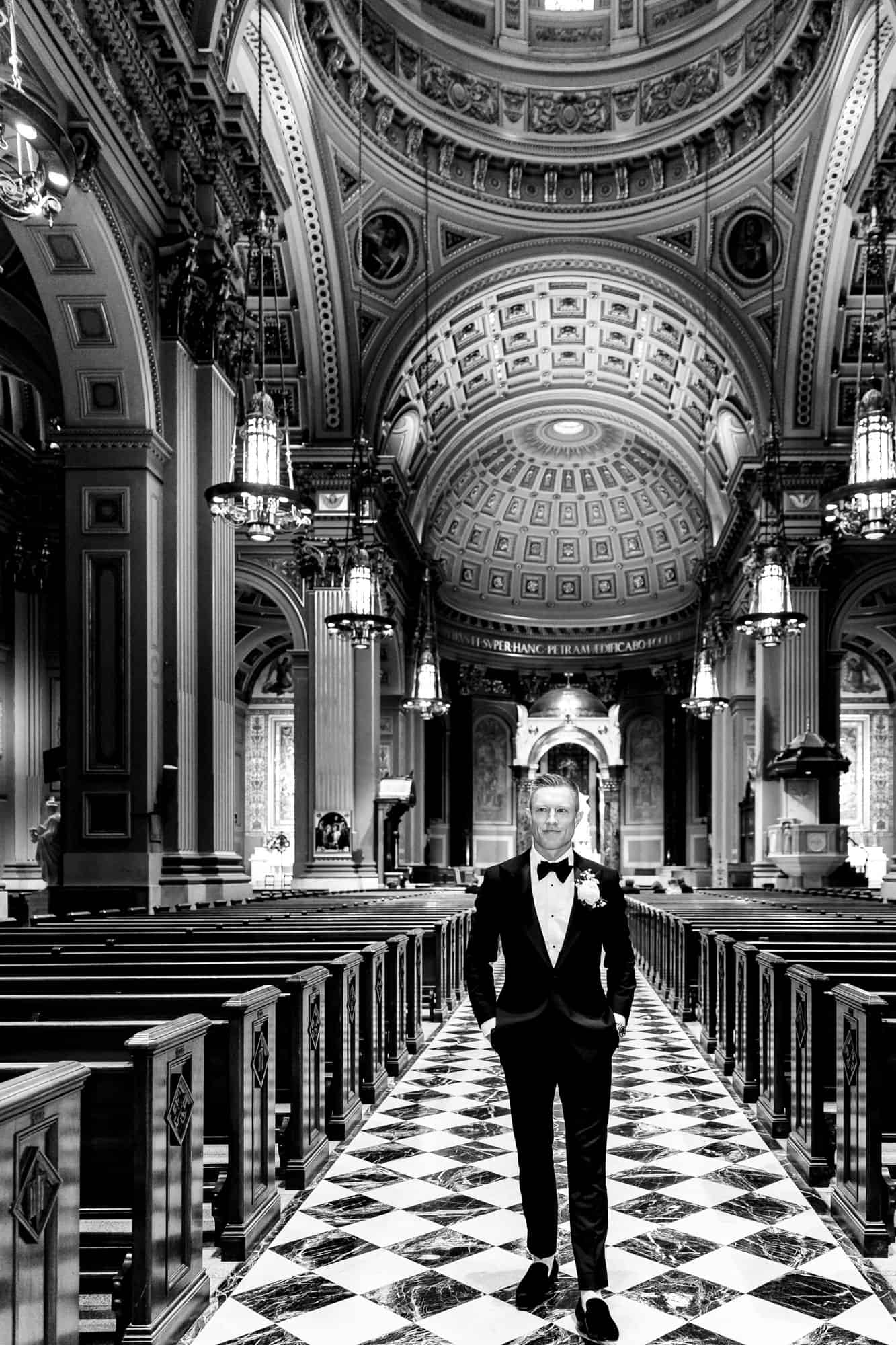 black and white shot of the groom posing inside the cathedral