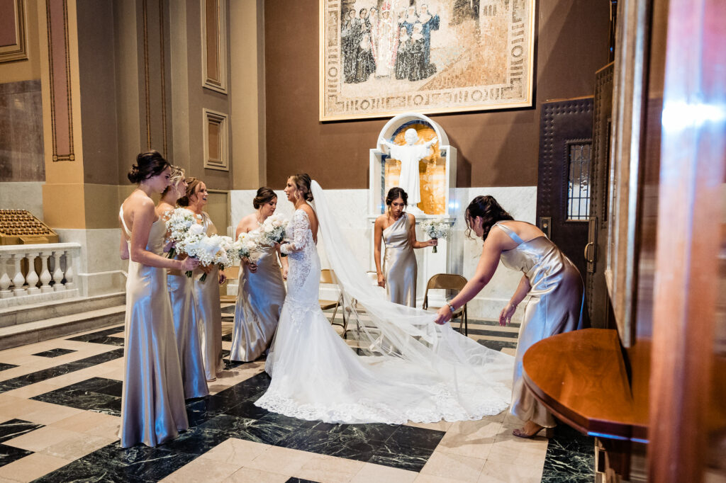 bridesmaids heping the bride with her dress before the wedding