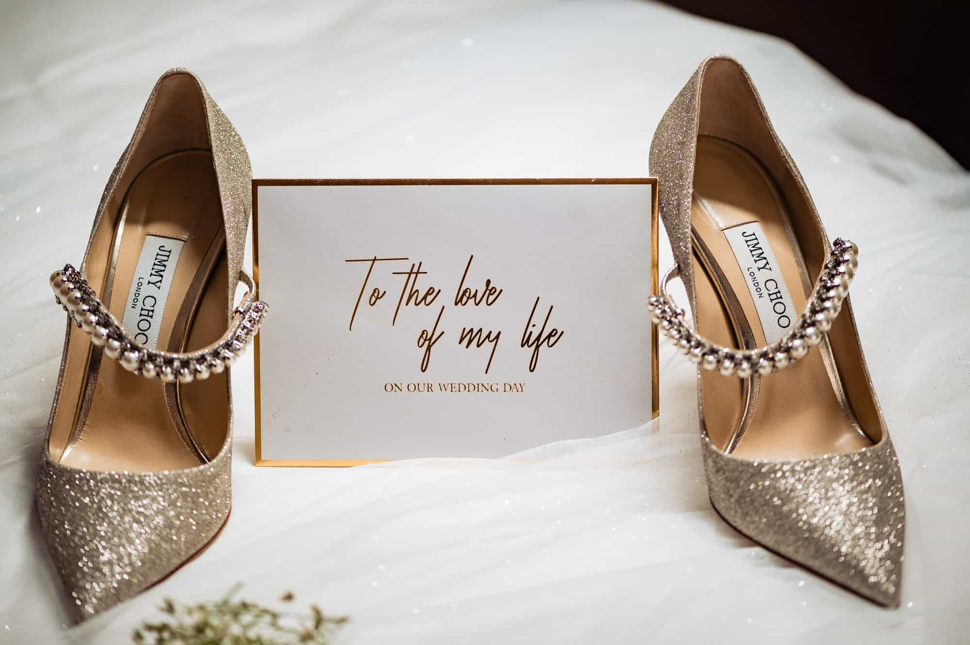 a wedding note placed in between a pair of glittering bridal shoes