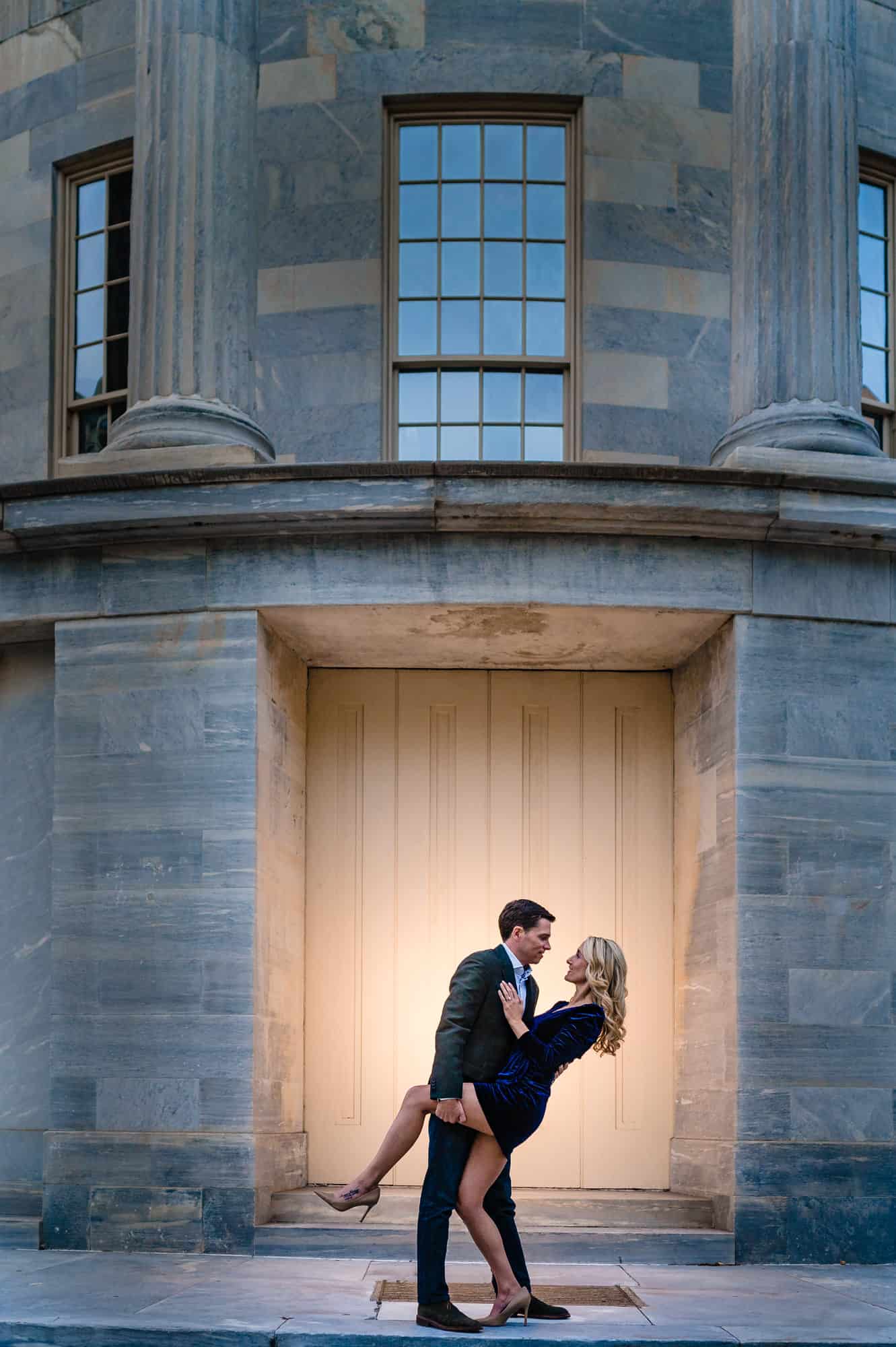 couple taking a pose with the Merchant Exchange Building in Philadelphia serving as their backdrop