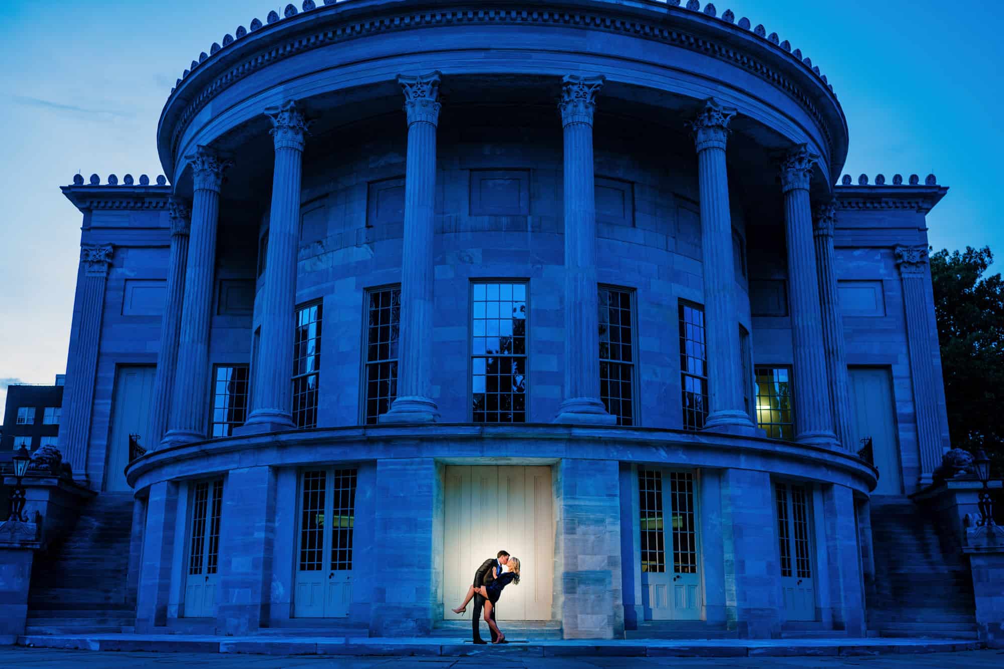 Philadelphia's Merchant Exchange Building is the backdrop for this couple's kiss during their old city engagement shoot