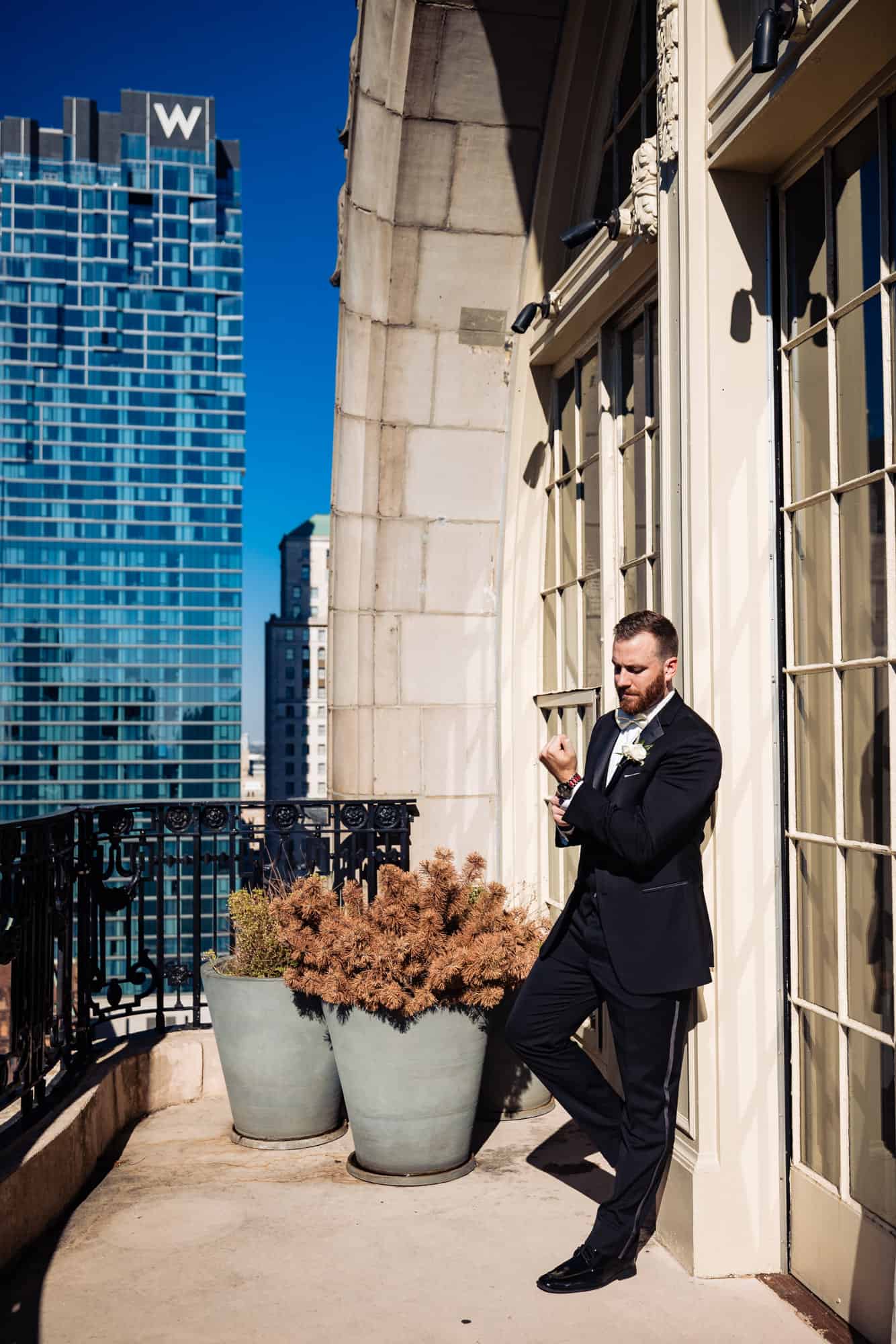 Groom leaning on the wall while fixing his cuff