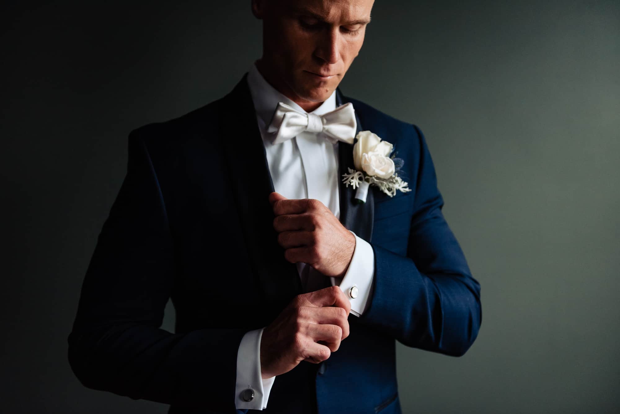 groom poses for the camera while fixing his sleeve