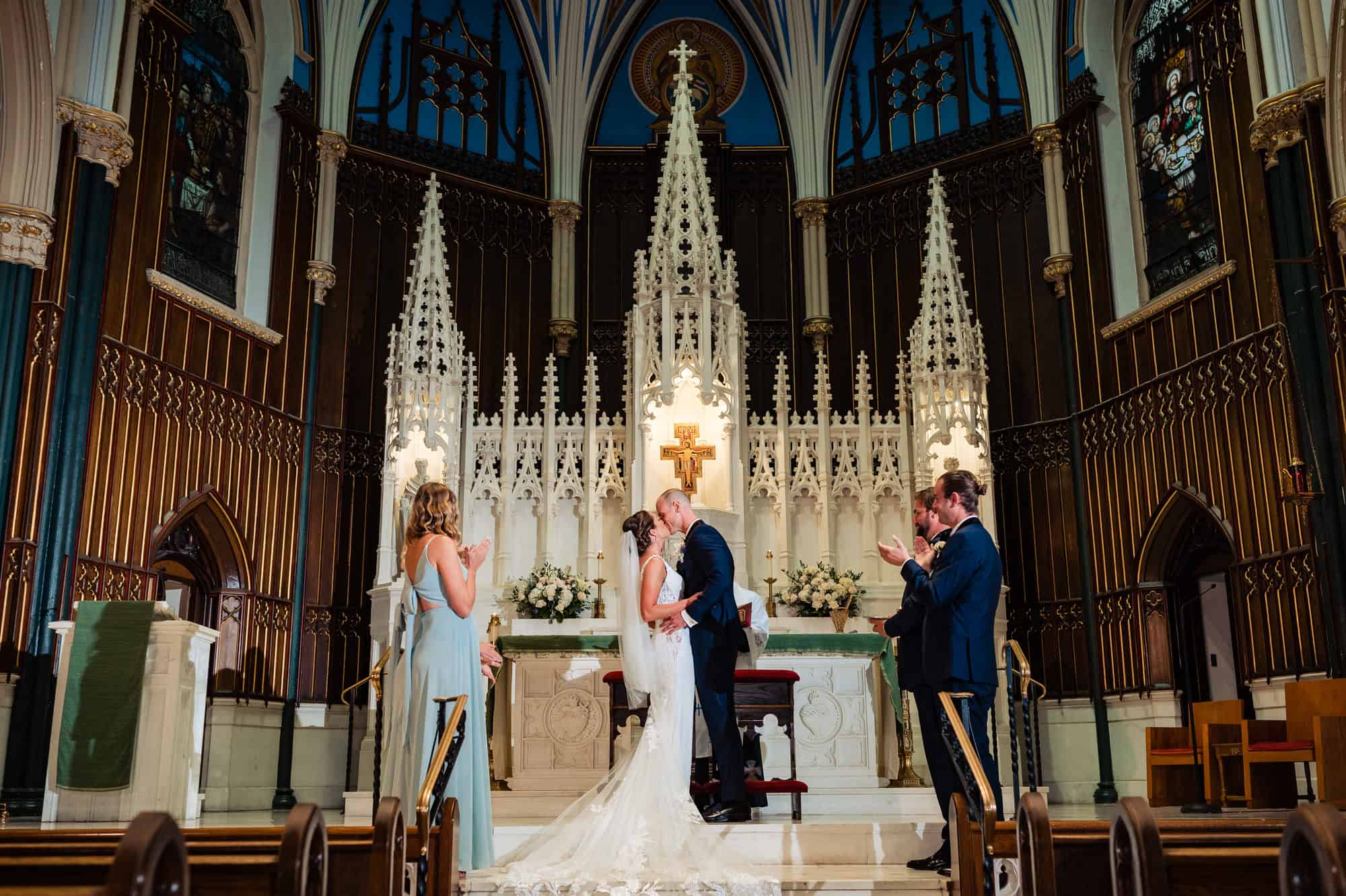 wide shot of the newlyweds kissing at the altar