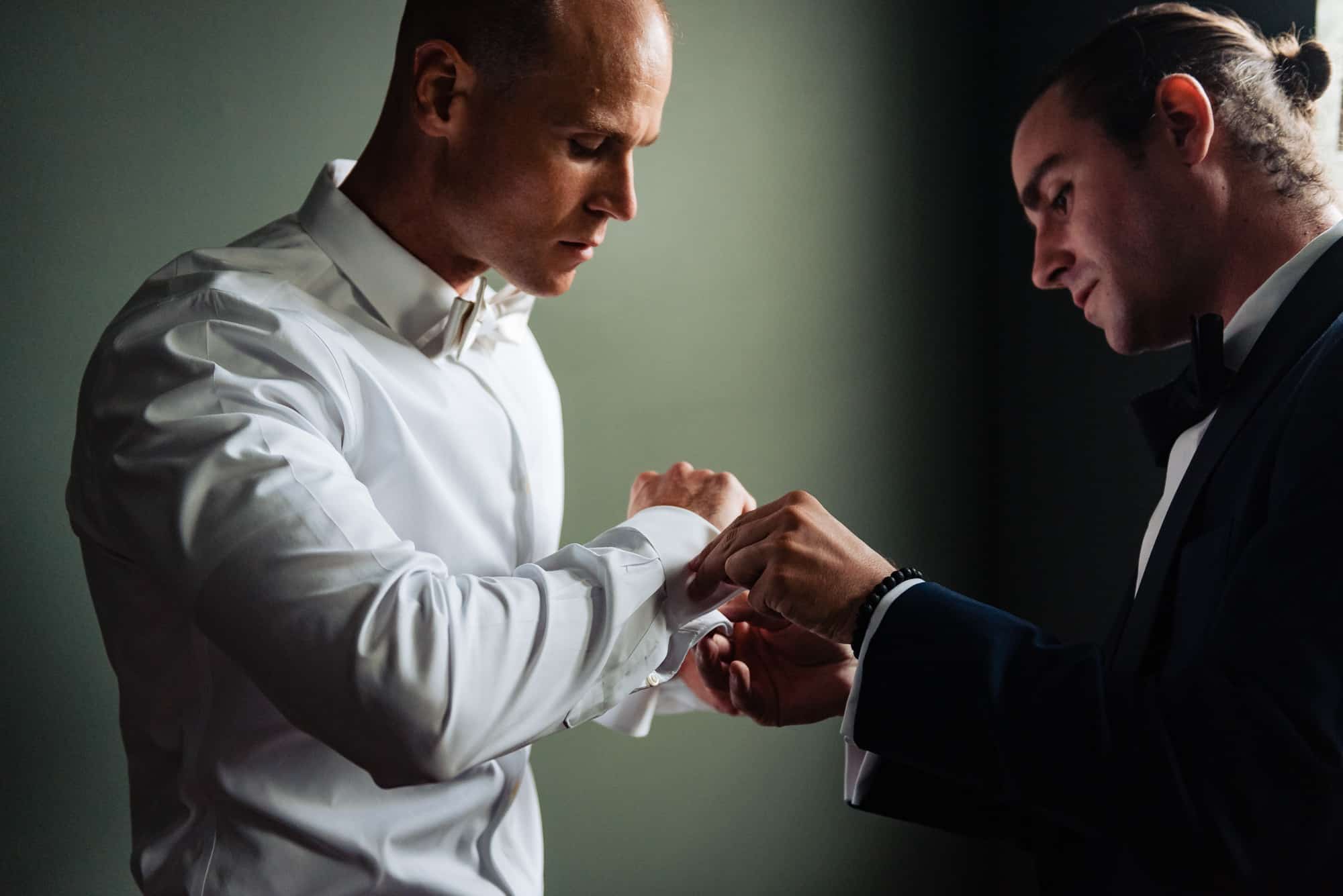 groomsman helping the groom with his sleeve