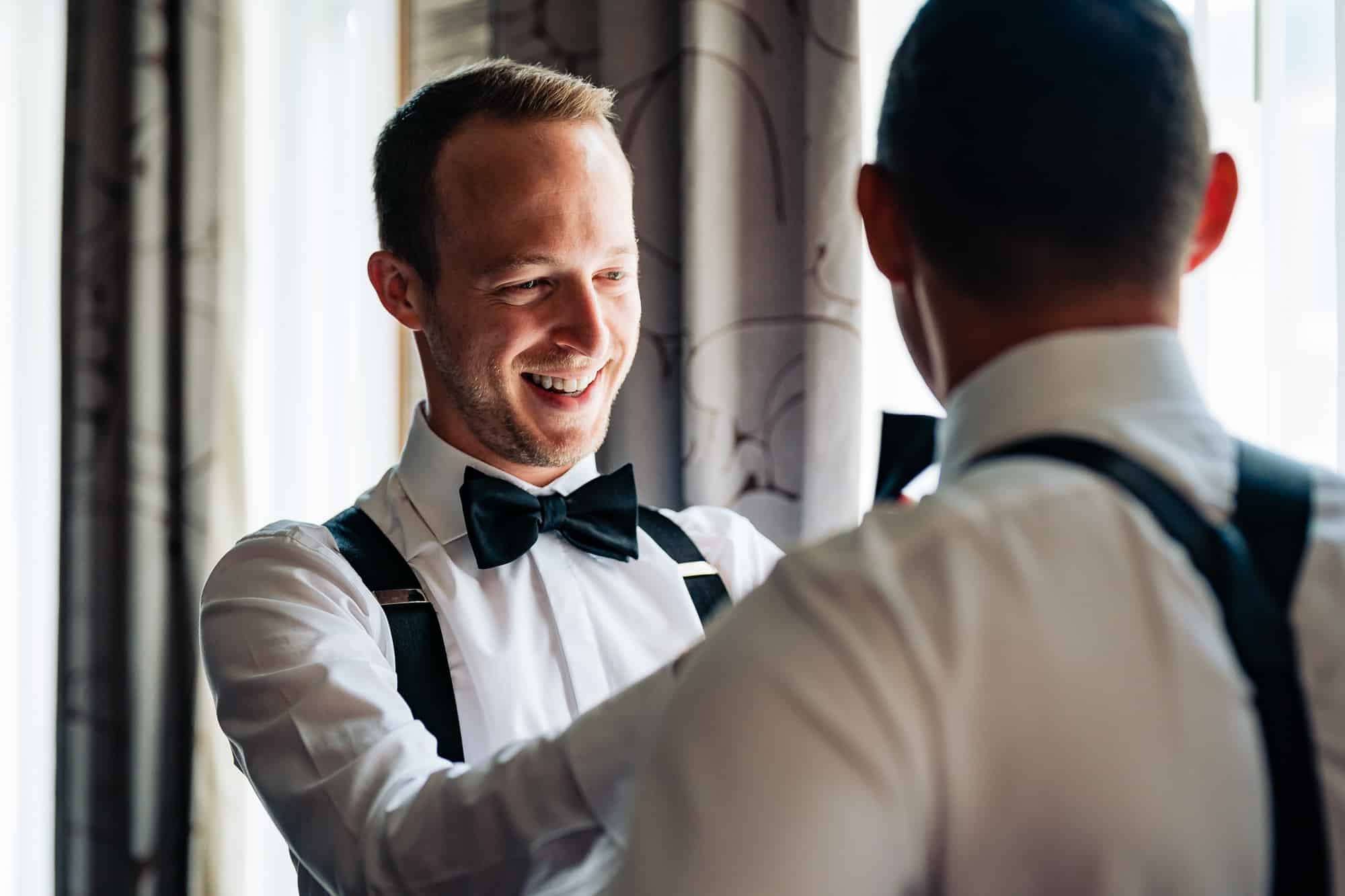 groom getting ready with the help of his bestman in their rittenhouse hotel executive suit