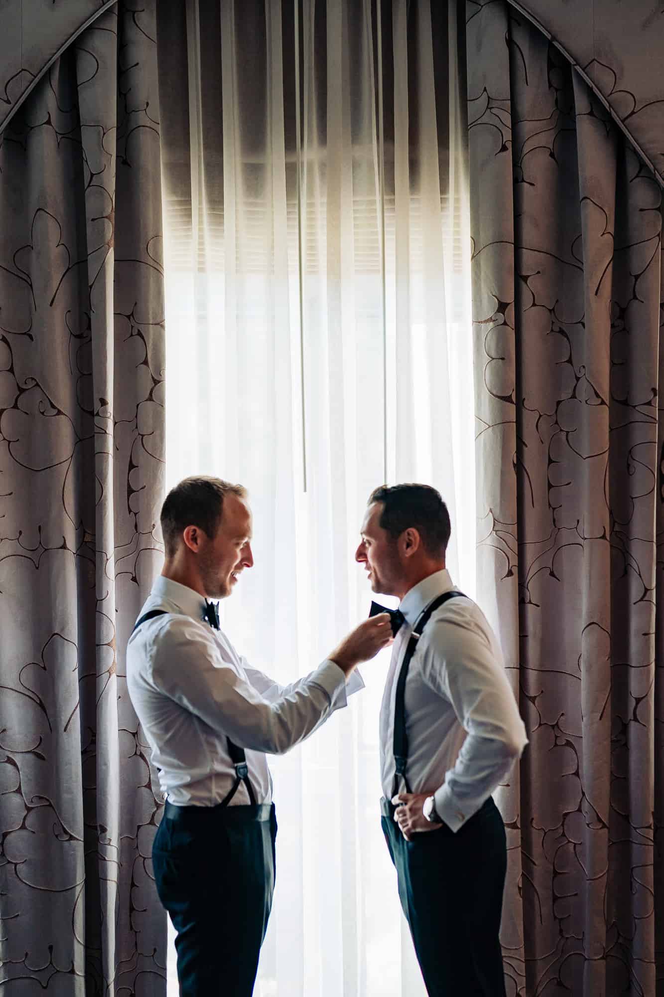 groom getting ready with the help of his bestman in their rittenhouse hotel executive suit